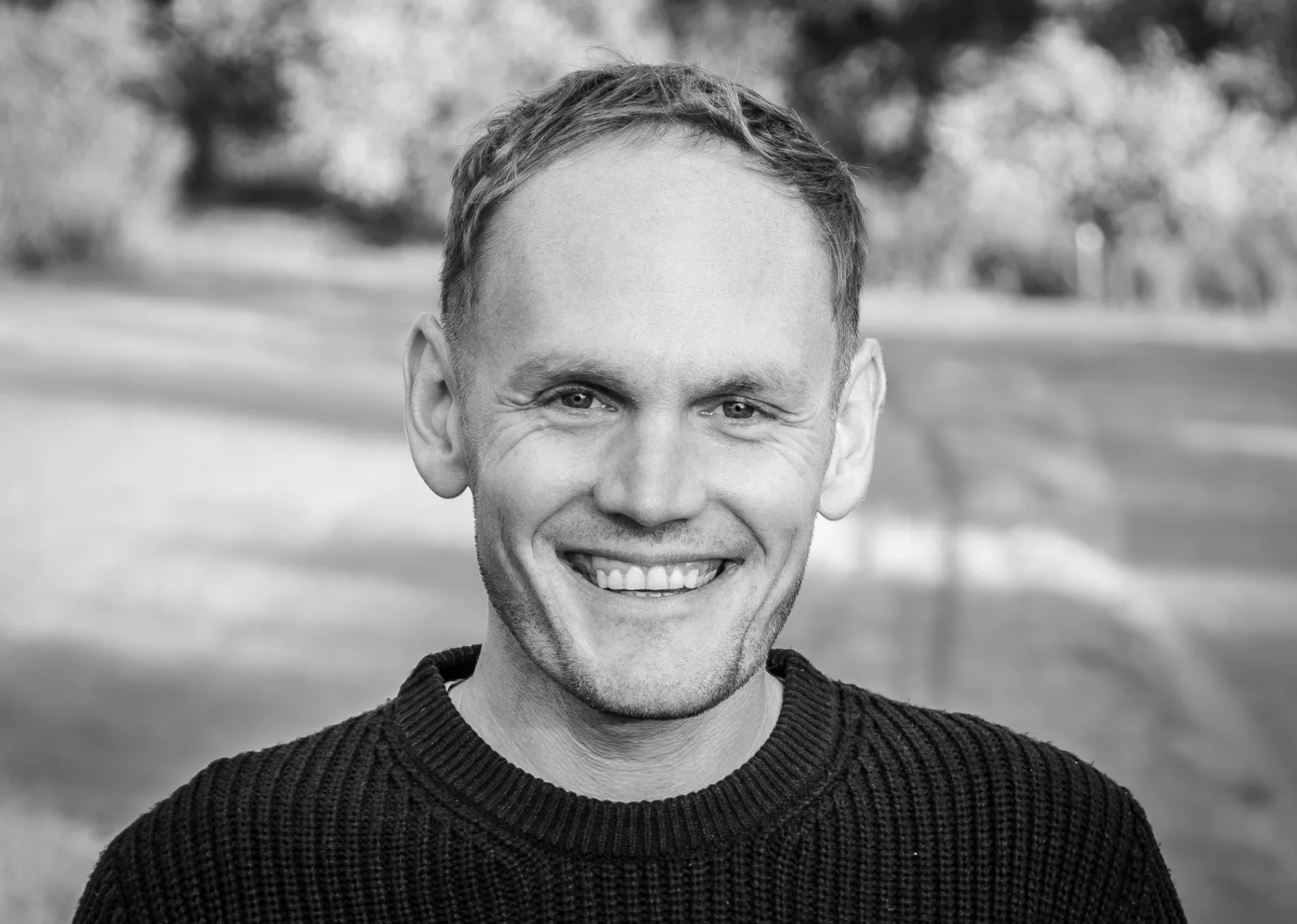 Andrew Brady, smiling, in a black jumper