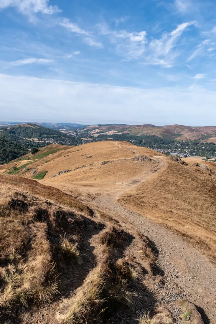 A hill path winding along a ridge towards a distant valley